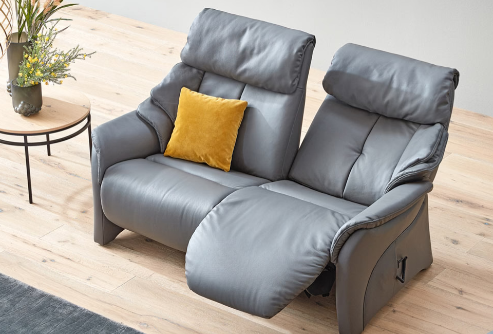 The Chester collection features a range of unique, patented reclining functions designed to deliver exceptional comfort and support. Complete the look with coordinating functional chairs, swivel recliners, and matching trapezoidal tables from Himolla.
The manual CUMULY function allows you to adjust the backrest effortlessly using a gas spring mechanism, activated by a convenient release loop, while the leg rest adjusts smoothly through gentle body pressure. Prefer effortless control? The electric version enables independent adjustment of both the backrest and leg rest at the touch of a button using an easy-to-use remote control.